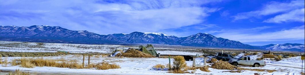 A landscape picture of the desert with snow and mountains on the horizon